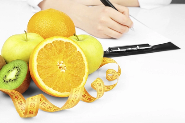 frutas y cinta métrica con mujer escribiendo